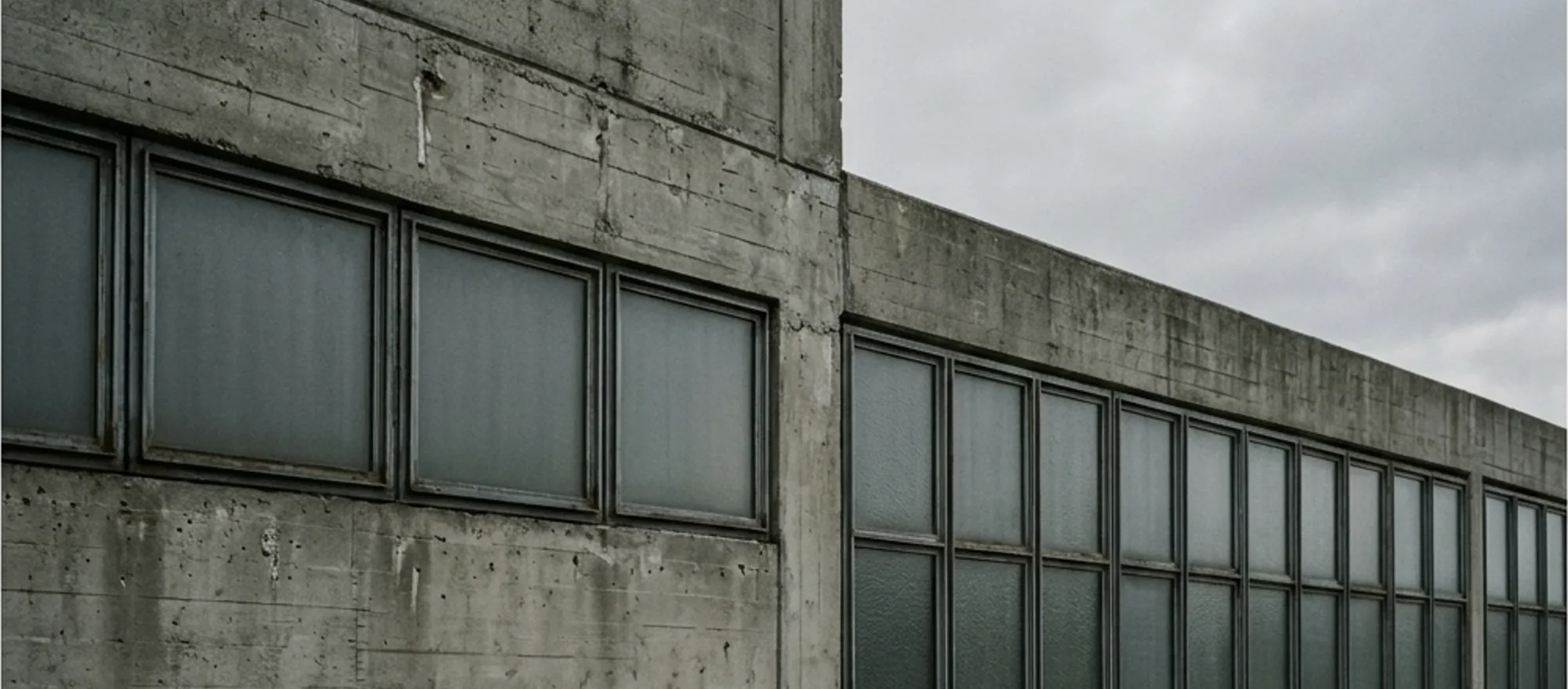 Concrete and glass building exterior under overcast skies.